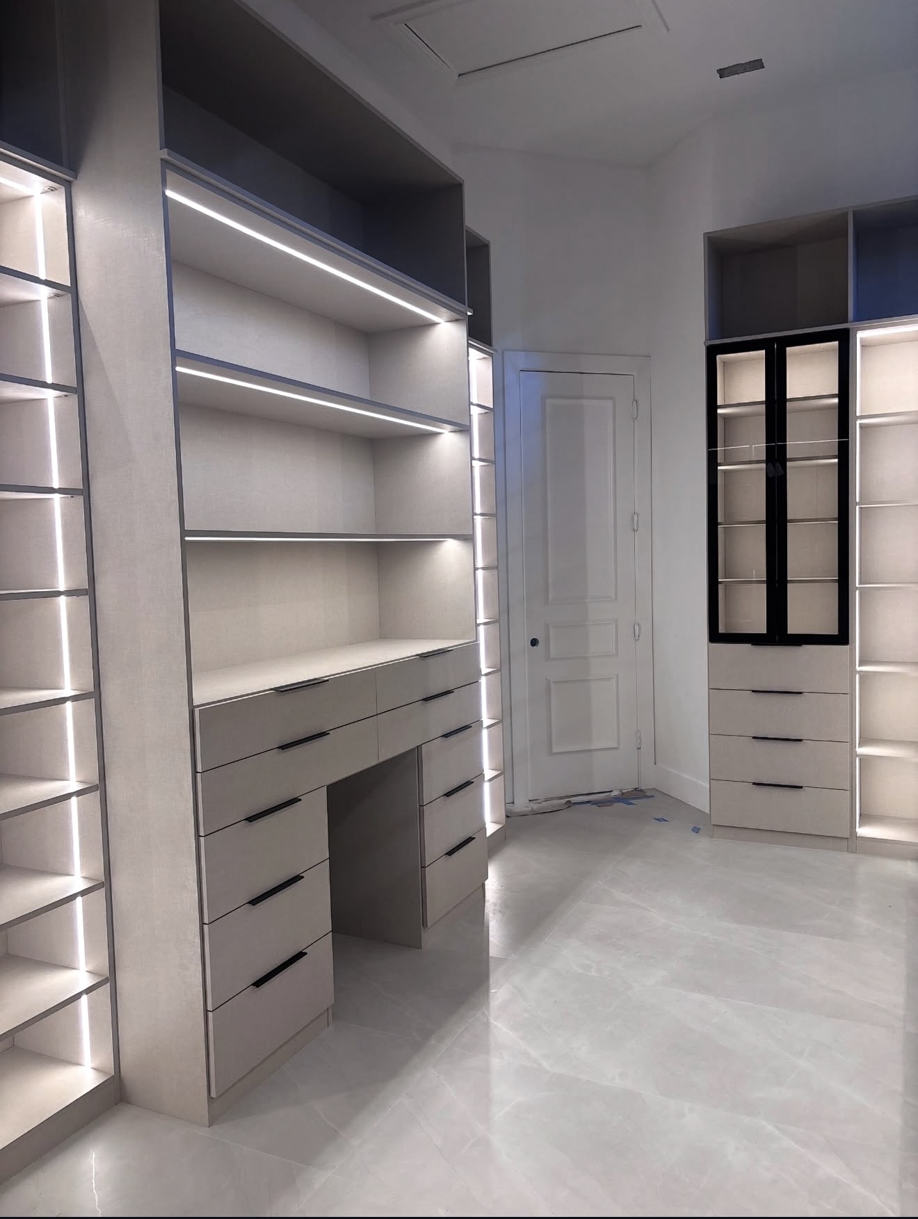 Luxury custom closet with illuminated shelving, vanity and glass display cabinetry
