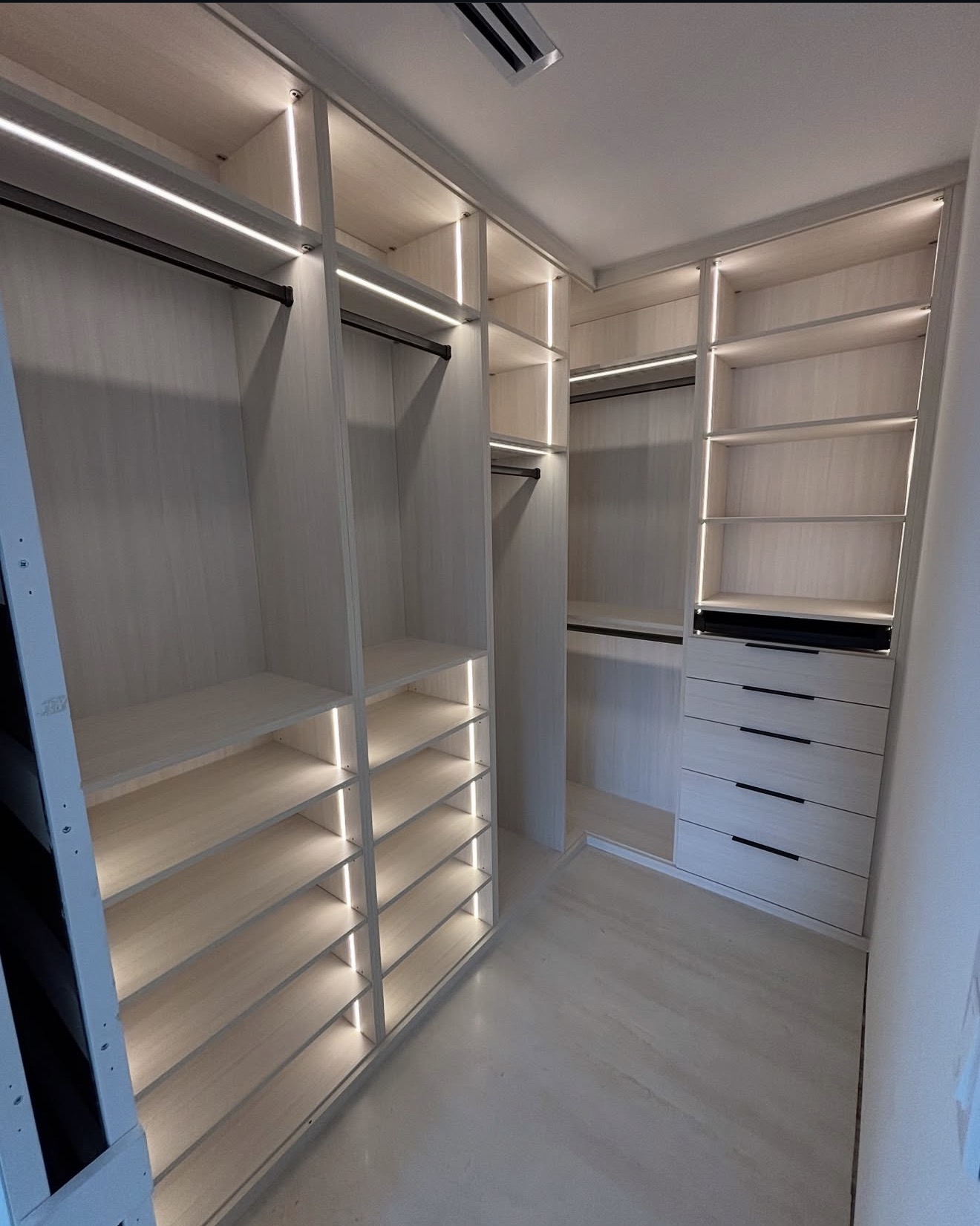 Custom walk-in closet with integrated LED lighting, hanging storage and drawers